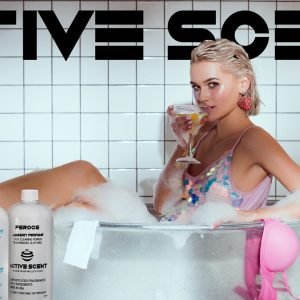 beautiful young woman holding cocktail glass and looking at camera in wash tub in bathroom